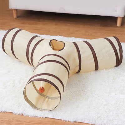 Tunnel pour chat en Y posé devant un canapé blanc